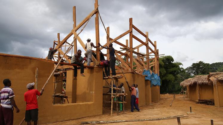 Photo of Ilima Primary School, Community Members hoisting the truss for the school roof