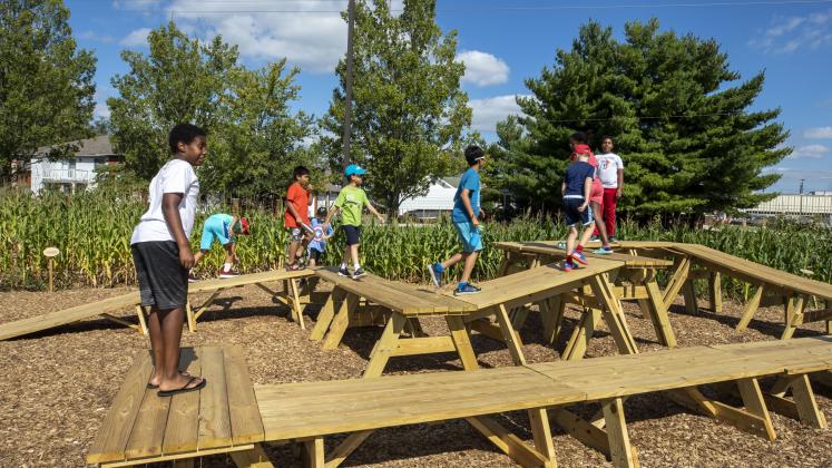 Children from Central Middle School playing on the picnic tables in our Corn / Meal installation